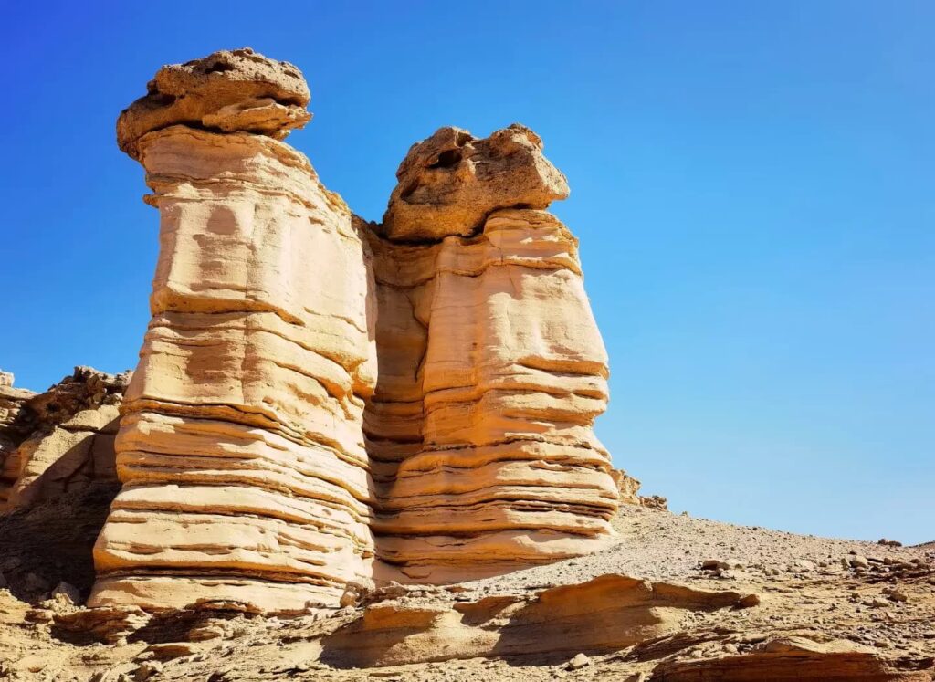 Two weathered sandstone pillars on a stony desert plain in Xinjiang