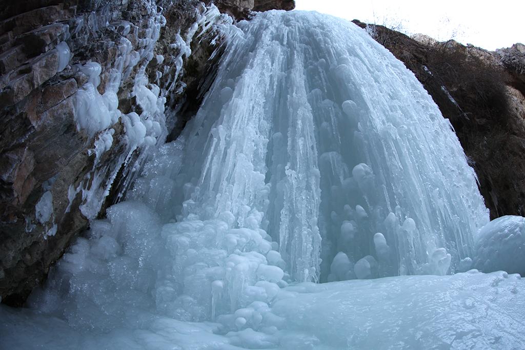 Waterfall frozen solid against a rock face during a Xinjiang winter