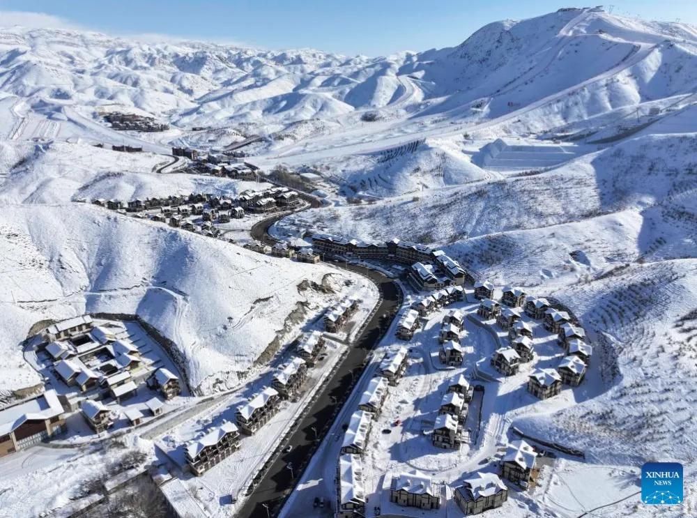 Snow-covered mountains and a valley settlement in Xinjiang, similar terrain to the Qarqan River headwaters